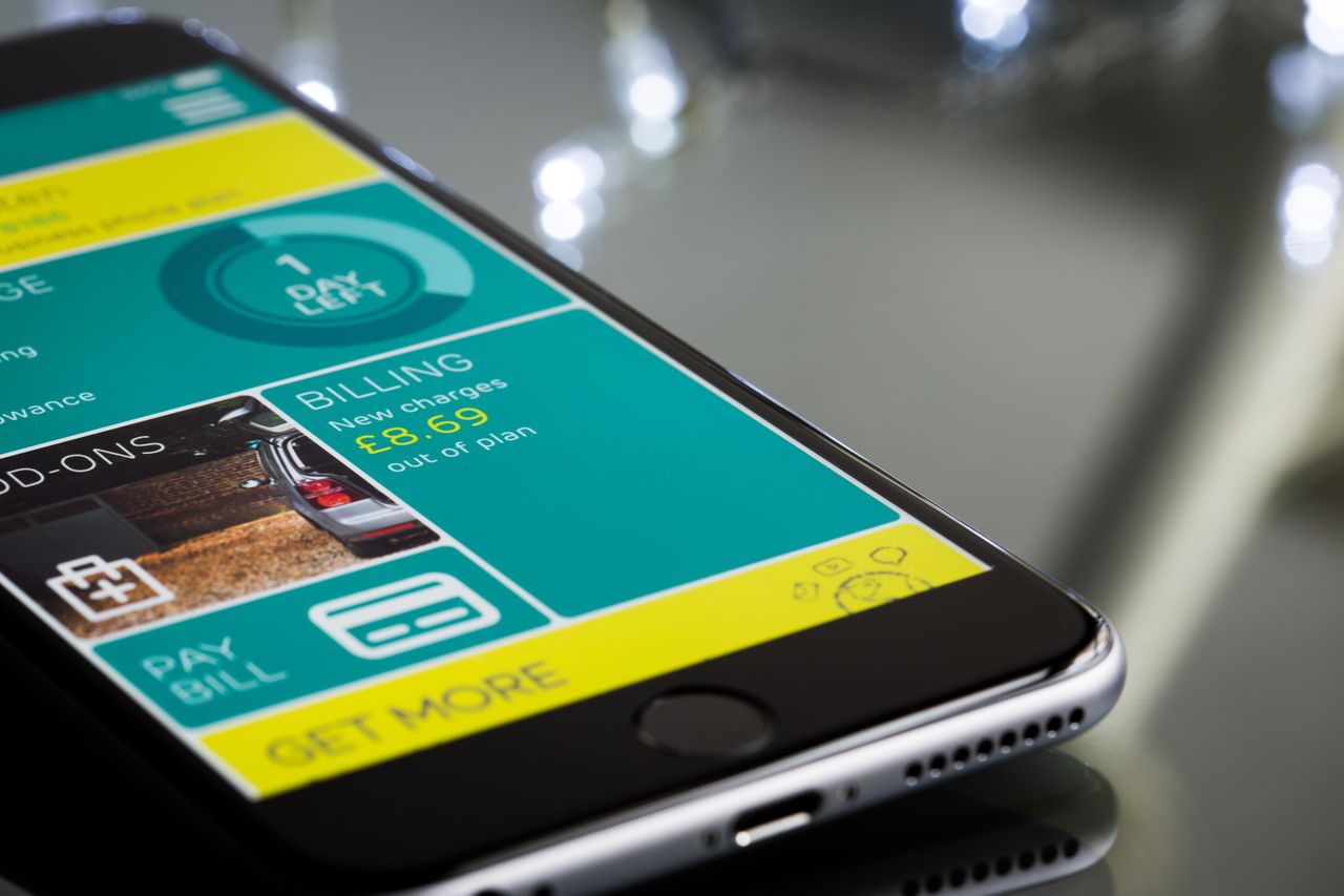 About Close-up of a smartphone displaying a billing app interface on a reflective surface.