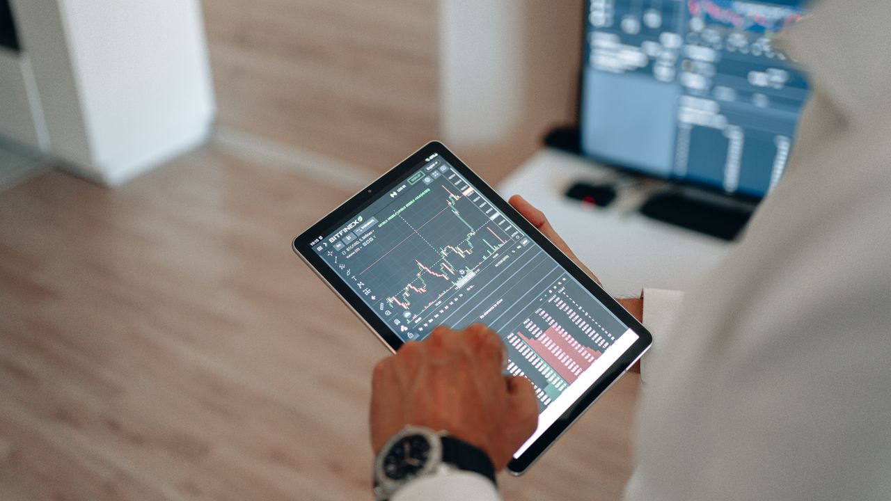The Art of Drawing Readers In: Your attractive post title goes here Close-up of hands using a tablet for online trading and market analysis.